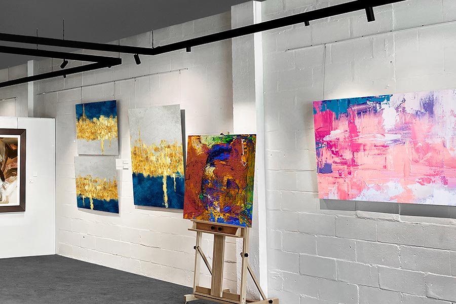 Track lighting highlights textured wall art in a modern gallery