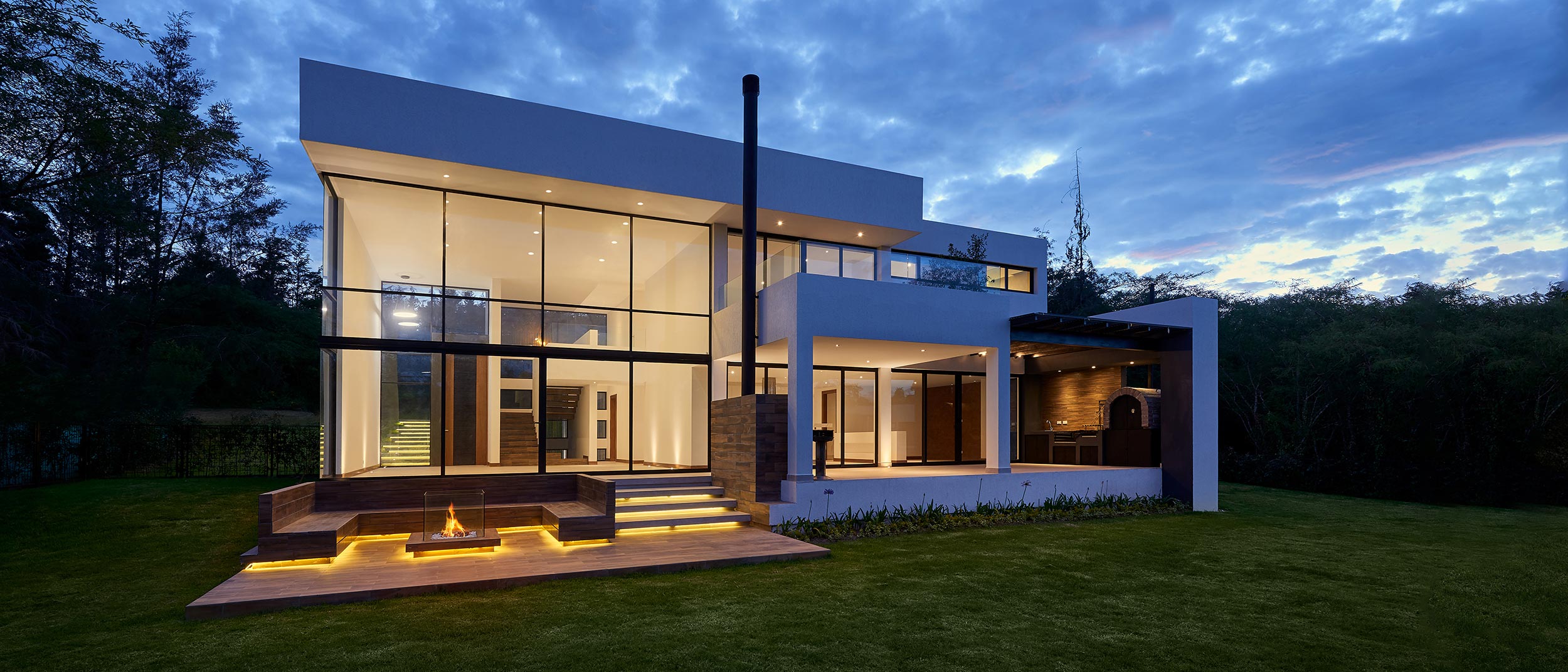 Modern home exterior with glowing step and patio lighting at dusk