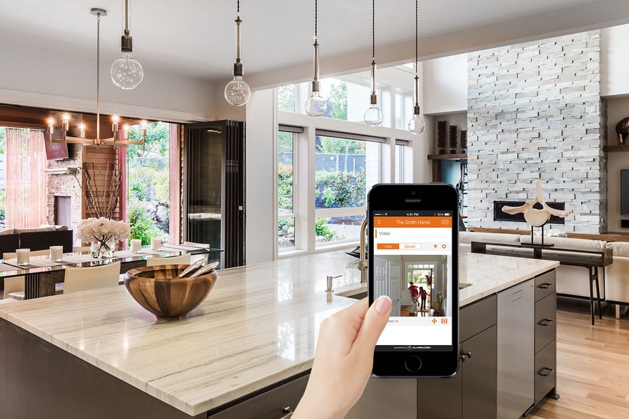 a hand holding a smartphone displaying footage of the front door of a home