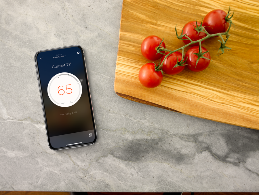 a smartphone on a kitchen counter next to a cutting board with tomatoes on it