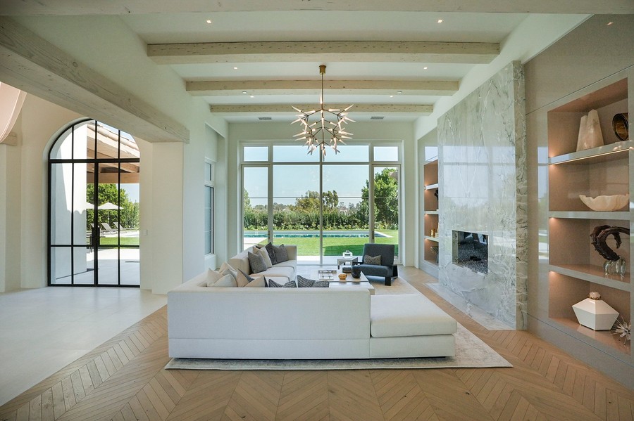 a living room with an L-shaped sofa, glass table, and bookshelves