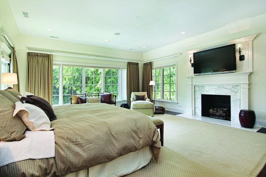 A bedroom with the curtains drawn and the lights on.