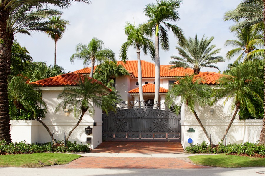 A Spanish-style home in Las Vegas with palm trees and a large front gate. 