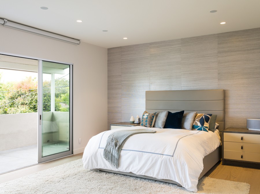 a well-lit bedroom with a large bed and a sliding glass door.