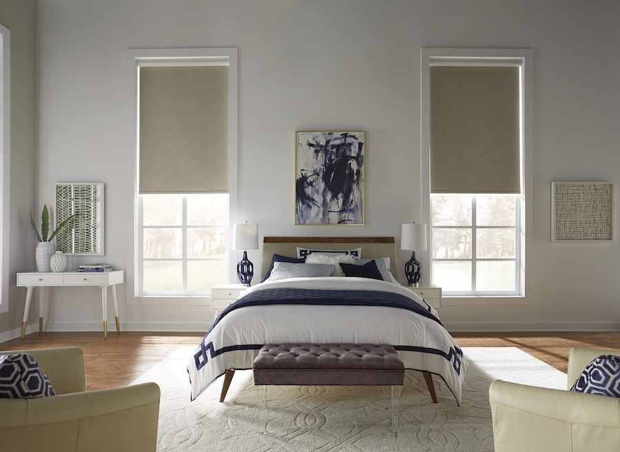A beautiful bedroom with floor-to-ceiling windows along the walls, outfitted with motorized shades. 