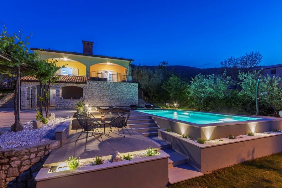 A home at dusk with landscape lighting illuminating the backyard.