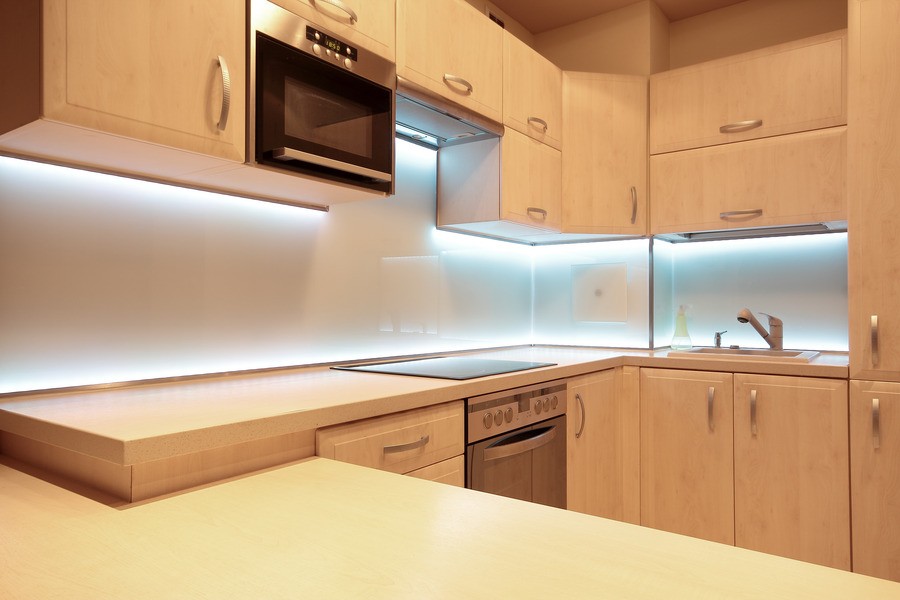 A bright kitchen featuring a countertop and cabinets, illuminated by modern LED under-cabinet lighting. 