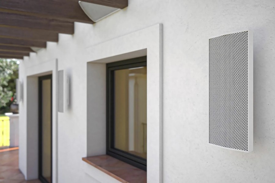 A close-up of a white outdoor speaker mounted on a patio wall. 