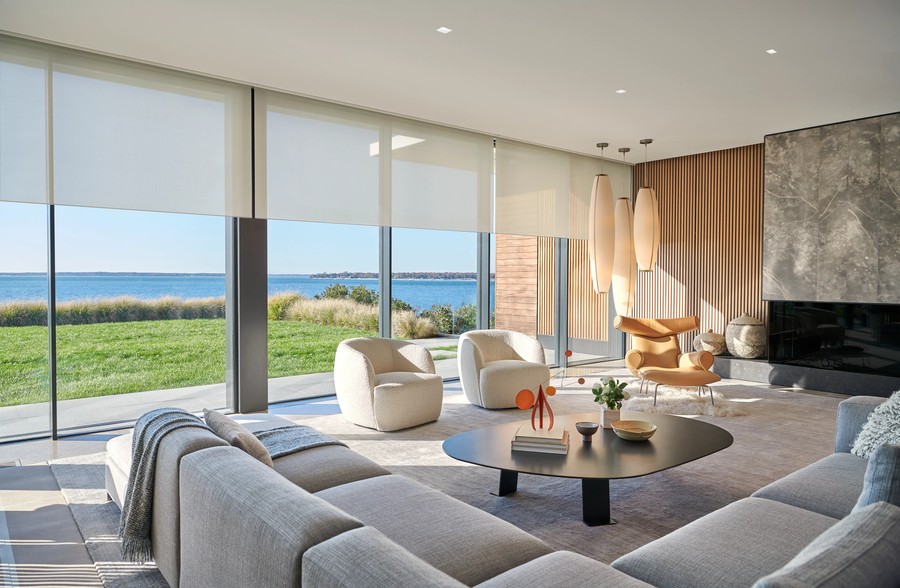 A living room illuminated by natural light and Lutron’s recessed lights. Lutron’s motorized shades are half-drawn over the windows.